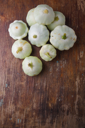 Heap of Patissons, some green pattypan or scallop squashes on old brown wooden rustic table background, copy space. Top viewの写真素材