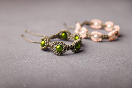 Two beaded bracelets from macrame yarn on gray background. Soft focused shot. Friendship wristbands.の写真素材