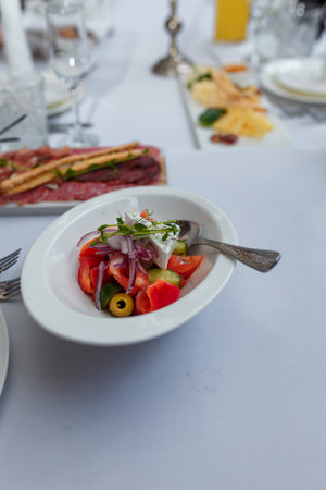 Greek salad in white plate, appetizer decorated with pea microgreen.の写真素材