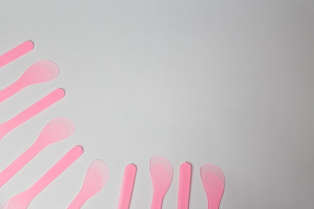 Several pink plastic disposable cosmetic spatulas for wax depilation or sugaring on white background. Beauty procedures, skin care. Copy space. Corner.の写真素材