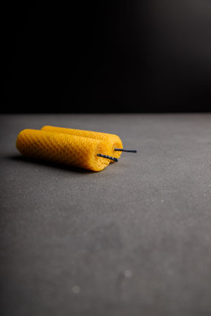 Two yellow textured candles made from natural bee wax on gray wooden background, copy space.の写真素材