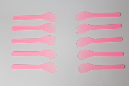 Several pink plastic disposable cosmetic spatulas for wax depilation or sugaring on white background. Beauty procedures, skin careの写真素材