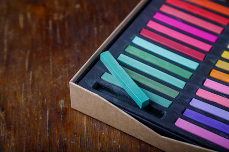 Box of professional multicolored dry pastel chalks or crayons sticks on wooden table background. Pastels for art drawing. Copy space.の写真素材