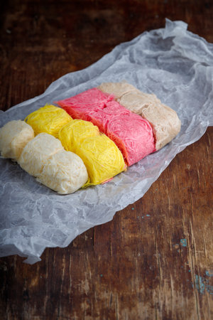 Multicolored pismaniye or pishmaniye also known as cotton candy, dragons beard or candy floss. Light halva, traditional Turkish sweets. Dessert on paper, wooden backgroundの写真素材
