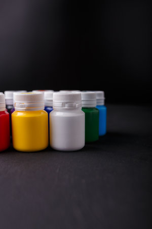 Small bottles of multicolored acrylic or gouache paint jars in a box on dark background. Art materials. Copy space.の写真素材