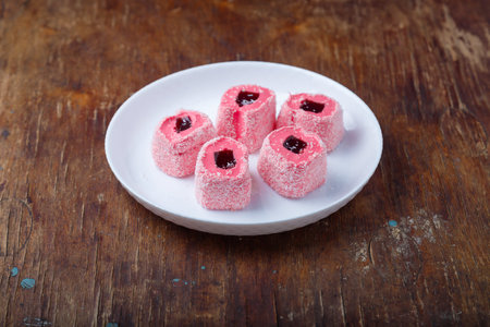 Turkish delight, pink and white locum roll with walnut and jelly on paper, wooden background....