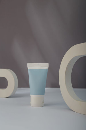 White blue Cosmetics tube mockup, concrete decorative elements on gray background. Unbranded beauty...