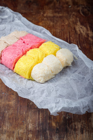 Multicolored pismaniye or pishmaniye also known as cotton candy, dragons beard or candy floss. Light halva, traditional Turkish sweets. Dessert on paper, wooden backgroundの写真素材
