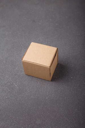 Cardboard box, square brown cardton container on gray background. No brand, no label. Copy space....