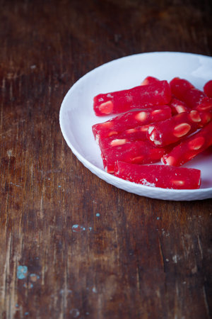 Turkish delight, red locum sticks with hazelnut on white plate, wooden background. Eastern sweets, oriental food. Traditional tasty dessert. Copy spaceの写真素材