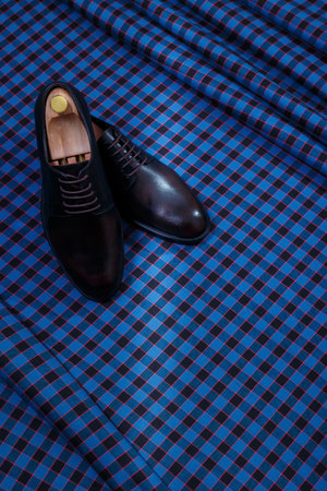 Male dark brown leather shoes on dark blue checkered suit fabric background. Copy space for logo, design, advertising. Classic formal accessories for men.の写真素材