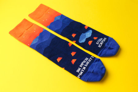 Pair of blue unisex socks on yellow background. Inscription in Ukrainian reads: If you want to see fire, be the sparkle.の写真素材
