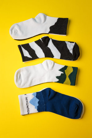 four pairs of socks with natural prints (mountain, zebra) on yellow background. Top view