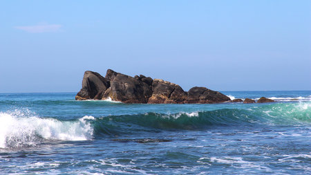 Coastal seascape with rocks jutting out of the water on the horizon and waves, clear blue sky. Natural seascape, wallpaper, shotsの写真素材