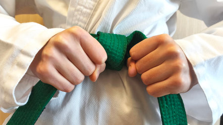 Close-up of a martial artist in a white kimono with a green belt. The fighter is in a defensive stance symbolizing strength, discipline and combat sports.の写真素材