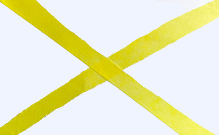 Yellow torn paper with ragged edges laid out in a cross, paper tape strips isolated on white backgroundの写真素材