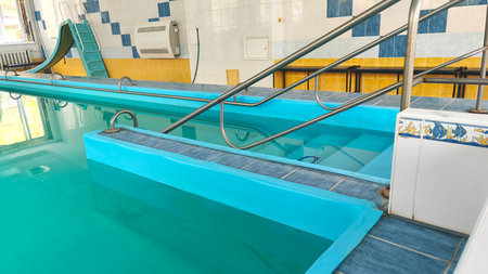 Indoor pool with stainless steel railings, blue water, filled with natural light for exercise, therapy and exciting water activities.の写真素材