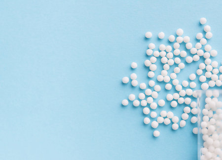 Different white pills and a plastic container on a blue background. medical themeの写真素材