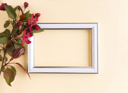 Beautiful flower arrangement. A branch of red flowers, an empty photo frame for text on a light...