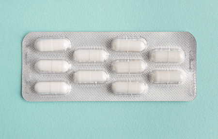 blister of white pills capsules on blue background