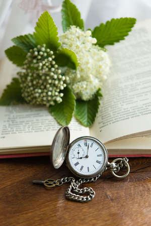 vintage old book with clock and flowers on wooden backgroundの写真素材