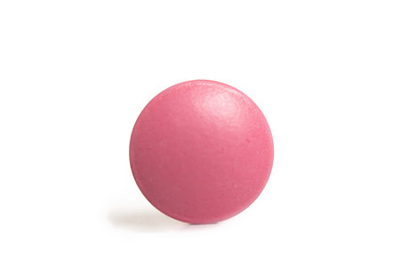Pink round medicine pill isolated on white background.