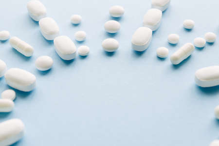 White pills on a blue background. Top view. Copy space.の写真素材