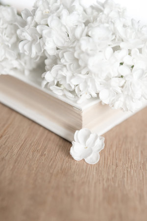 White lilac flowers and book on wooden background. Selective focus.