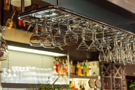 Empty wine glasses hanging on a bar counter in a pub or restaurantの写真素材