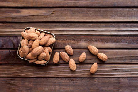 Almond nuts in a metal box on a brown wooden background.の写真素材