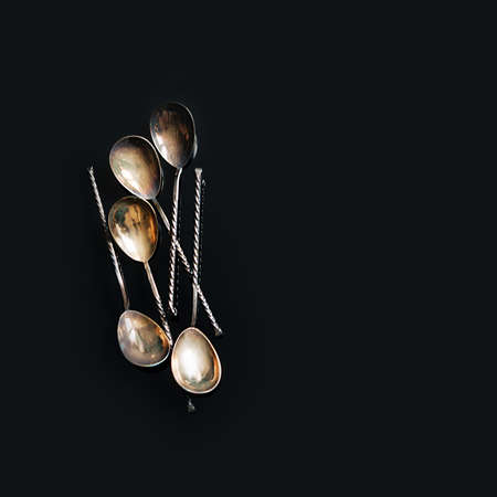 Vintage metal spoons on a black background, top view.の写真素材