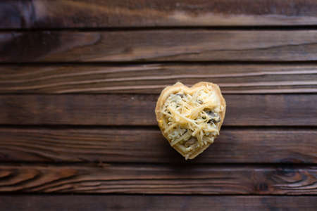 Heart shaped pizza with cheese on a wooden background. Top view.の写真素材