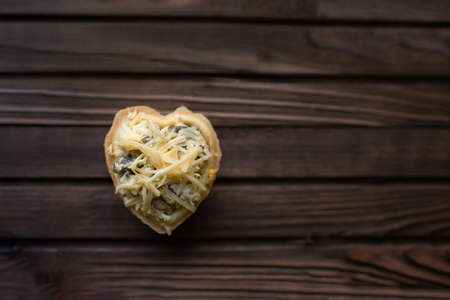 Heart shaped cookie with cheese and mushrooms on a wooden background. Top view.の写真素材