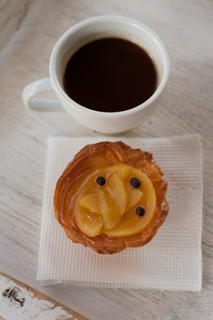 Small cupcake with peach with a cup of coffeeの写真素材