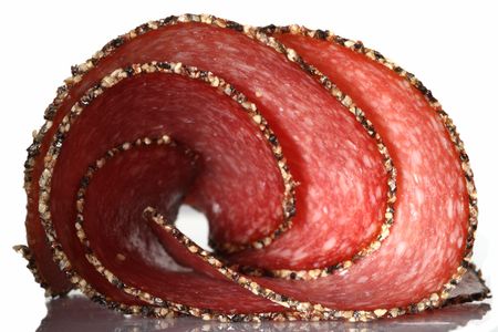 german pepper salami sausage, sliced, twisted, isolated on white, with shadowの写真素材