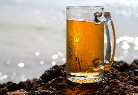 cold beer cider glass on a cliif, shiny sea on background, shallow DOFの写真素材