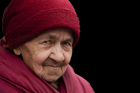 old grandma in red headscarf with piercing look, isolated on blackの写真素材