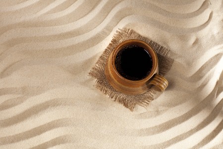 black coffee in mug on beach sand background, top viewの写真素材