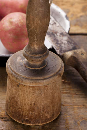 antique potato masher on  old wooden table with knife and potato, shallow dofの写真素材