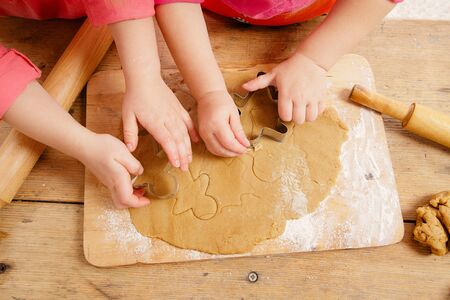 little girls cutting christmas  gingerbread cookies, hands onlyの写真素材