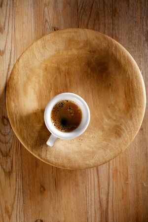 espresso coffee in thick white cup on old wooden plateの写真素材