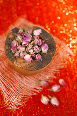 rose tea buds in wooden bowl, red glitter background, shallow dofの写真素材