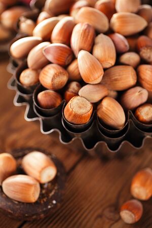 wild hazelnut in iron bowls  on wooden tableの写真素材