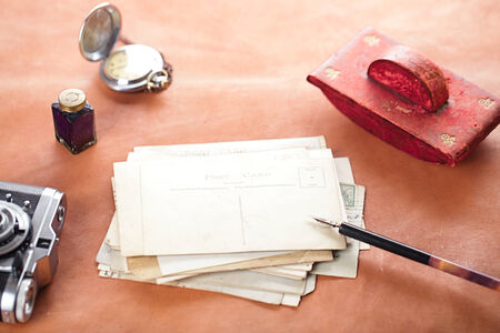 retro photo post cards , vintage ink , pen, blotter and camera on old leather tableの写真素材