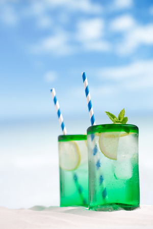 mojito cocktail with ice, rum, lemon and mint   in a  glass  on beach sand and seascapeの写真素材
