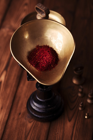 saffron spice in antique vintage iron scale bowl  on wooden table, shallow dofの写真素材