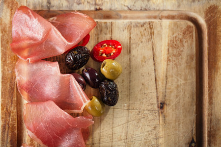 meat platter of Cured Meat and olives on old wooden boardの写真素材