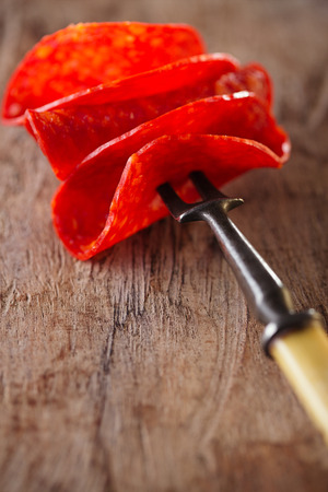 chorizo pamplona salame on meat fork and old woodの写真素材