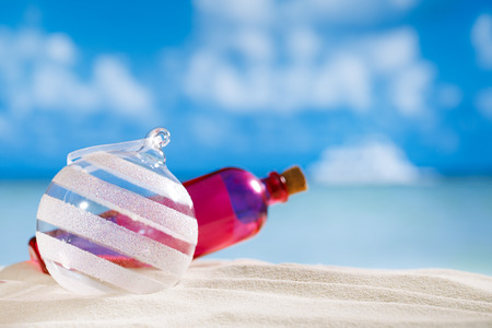 glitter christmas glass ball and bottle on  beach with seascape backgroundの写真素材