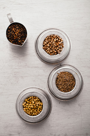 coriander seeds black and white, cardamom and cumin in   in vintage  old dishes,  tin metal background, closeupの写真素材